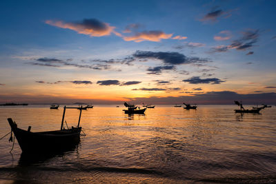 Silhouette boats in sea against sky during sunset