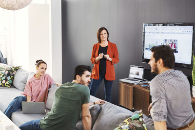 Business people listening to male colleague during presentation in office lobby