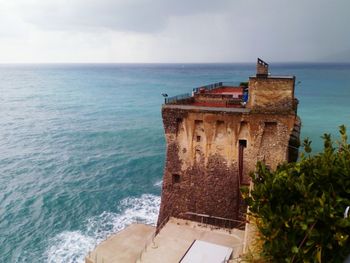 Abandoned building by sea against sky