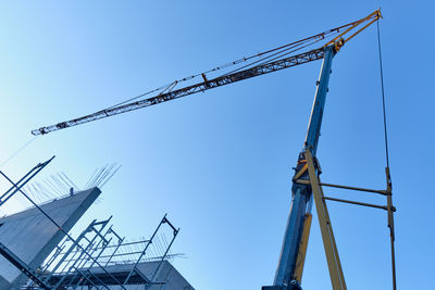 Low angle view of crane against clear blue sky