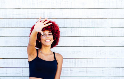 Portrait of a smiling young woman standing against wall