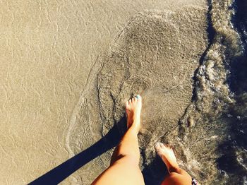 Low section of woman walking on shore at beach