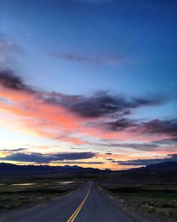 High angle view of road amidst field against sky during sunset