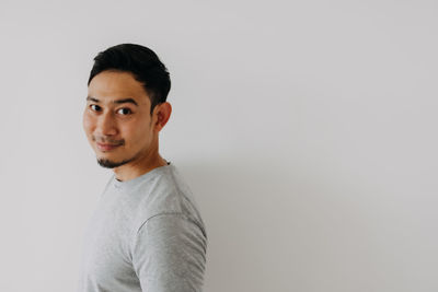 Portrait of young man standing against white background