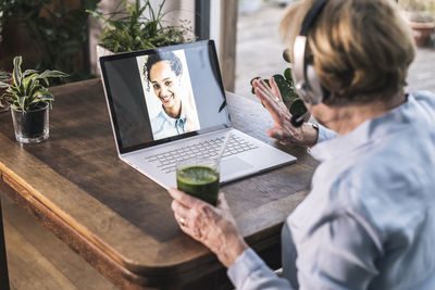 Rear view of man using laptop on table