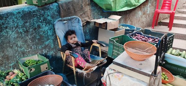 Portrait of girl sitting on chair in market