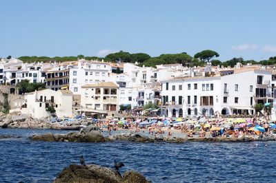 Buildings by sea against clear sky