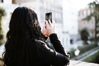 Rear view of woman photographing from mobile phone