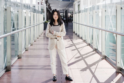 Portrait of beautiful chinese business woman holding tablet in building office. technology