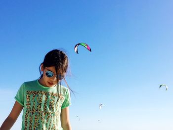 Low angle view of woman against clear blue sky