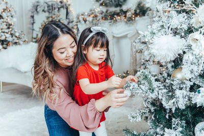 Portrait of smiling young woman holding christmas tree