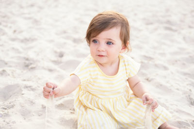 Cute girl sitting on sand at beach