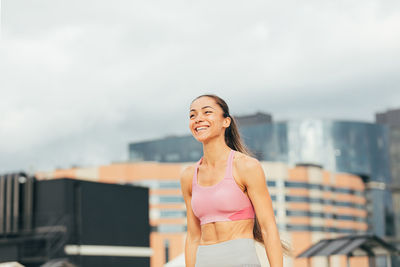 Portrait of young woman standing against sky