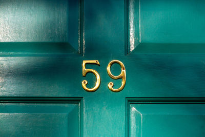 House number 59 on a turquoise wooden front door in london