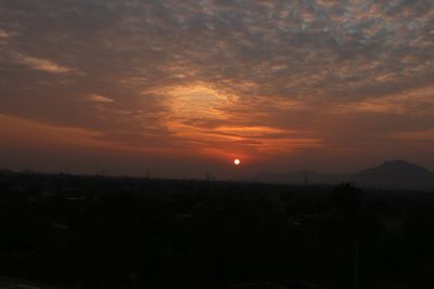 Silhouette landscape against dramatic sky during sunset