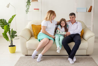 Full length of friends sitting on sofa