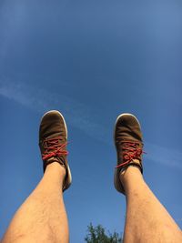 Cropped legs of man against blue sky