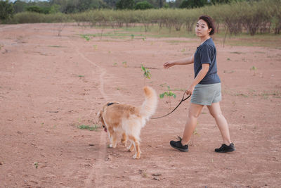 Woman with dog walking on land