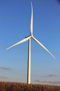 Wind turbine on field against blue sky