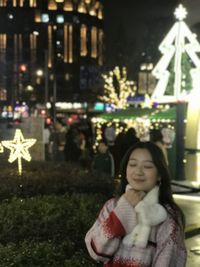 Portrait of beautiful woman standing in city at night