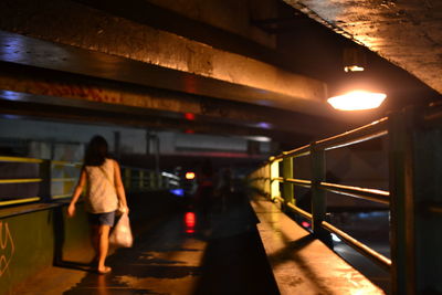 Rear view of woman walking in illuminated underground