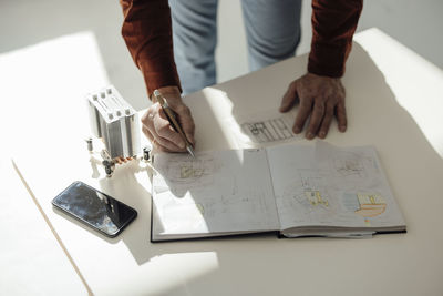 Hand of businessman writing in diary at desk