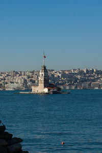 Sea by buildings against clear blue sky