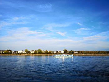 Scenic view of river by buildings against blue sky