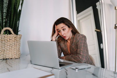 A stressed business woman works using a laptop phone and technology while sitting in the office