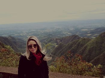 Portrait of young woman standing on mountain against sky