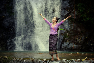 Woman with arms raised against river