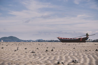 Boat moored on beach against sky