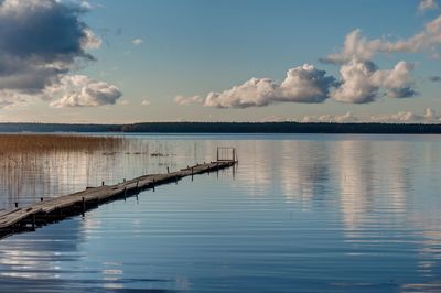 Wooden posts in lake against sky