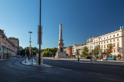 View of city street and buildings against blue sky