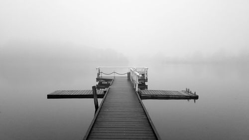 Pier on lake in foggy weather