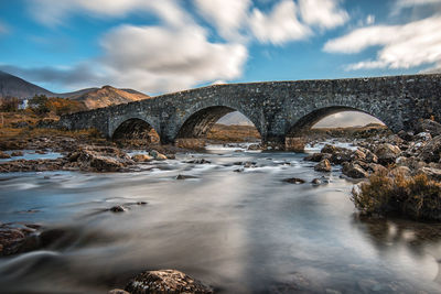 Arch bridge over river against sky