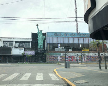 Statue by road against sky in city