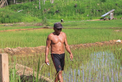 Rear view of shirtless man standing in field