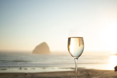 Close-up of champagne flute at beach against clear sky