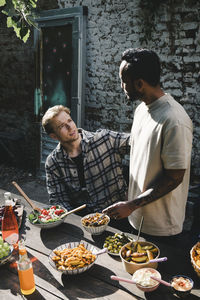 Young male friends talking to each other at garden party in back yard