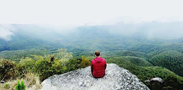 Rear view of man sitting on mountain road