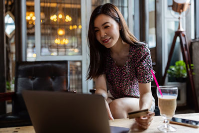 Smiling woman shopping online at cafe