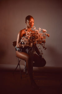 Young woman with flowers sitting on chair