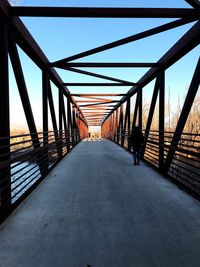 Rear view of footbridge along calm sea
