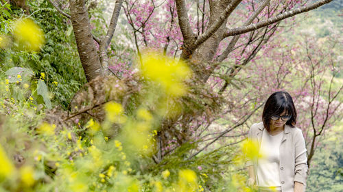 Low section of woman standing by flowering tree