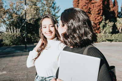 Smiling friends walking outdoors in sunny day