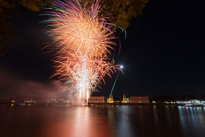 Firework display over river against sky at night