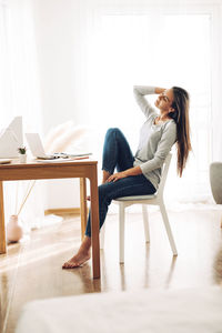 A beautiful girl is sitting leaning back in a chair and stretching after work at a laptop
