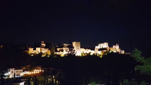 Illuminated buildings against clear sky at night