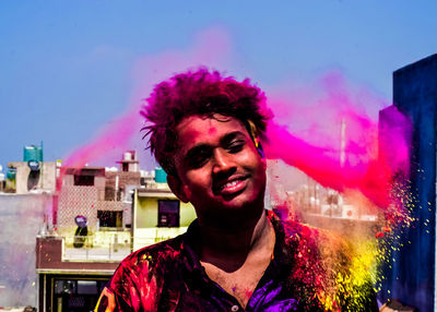 Smiling young man standing by powder paint during holi